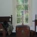 A view of the window inside of the room with a bust and a period trunk.